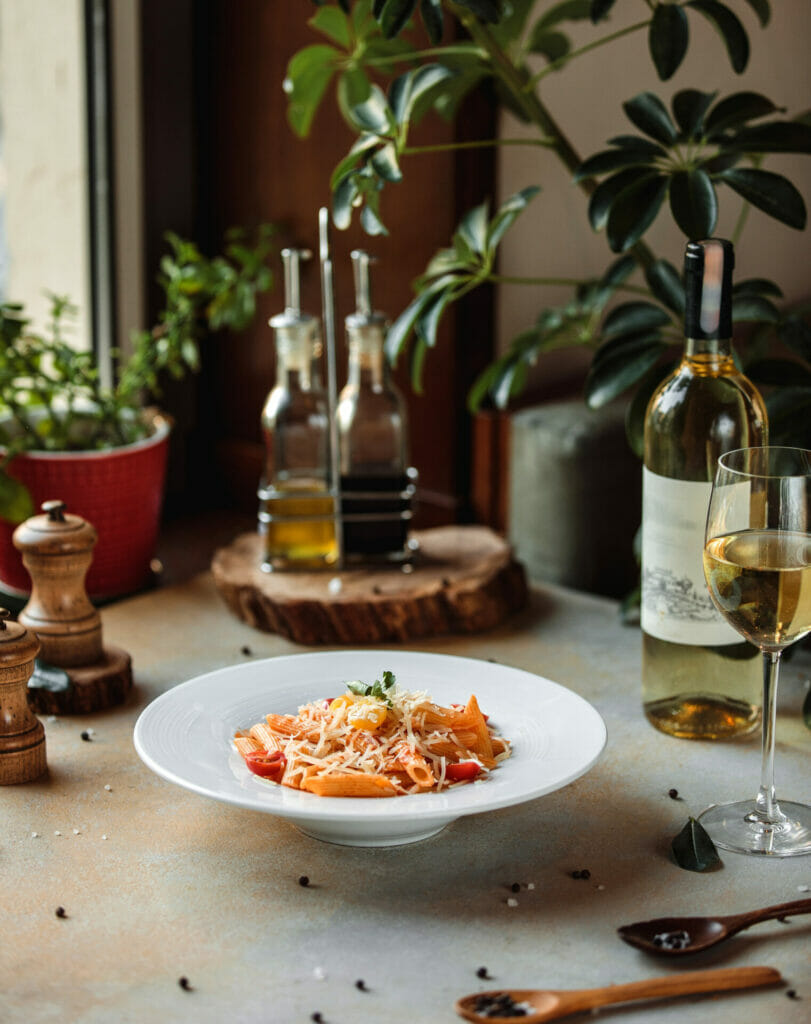 sideview of pasta with tomato sauce and parmesan cheese in a white bowl